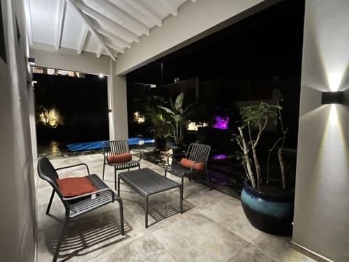 Patio couvert élégant au gîte Les Hébergements Passion avec transats, table à manger, plantes en pot et vue sur la piscine