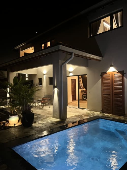 Vue nocturne du gîte Passion Vanille Cannelle en Martinique avec patio illuminé, piscine privée et séjour ouvert