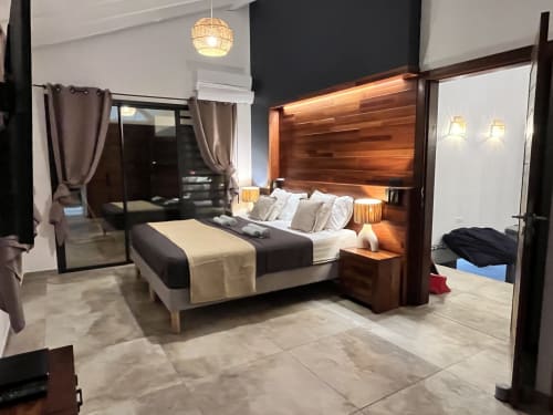 Chambre moderne du gîte Les Hébergements Passion en Martinique avec tête de lit en bois, lit king-size et décoration contemporaine