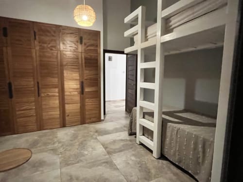 Spacieuse chambre de cottage aux Hébergements Passion avec armoire en bois, étagères blanches, sol carrelé et suspension