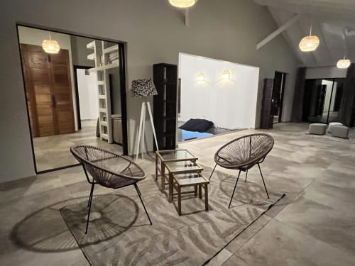 Salon moderne aux Hébergements Passion avec chaises tressées, décor minimaliste et éclairage ambiant en Martinique