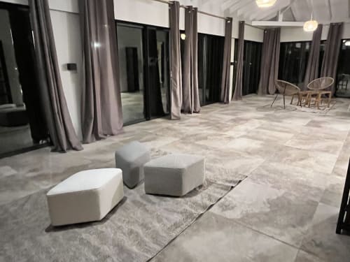 Terrasse moderne avec poufs en tissu gris, rideaux du sol au plafond et zone lounge aux Hébergements Passion