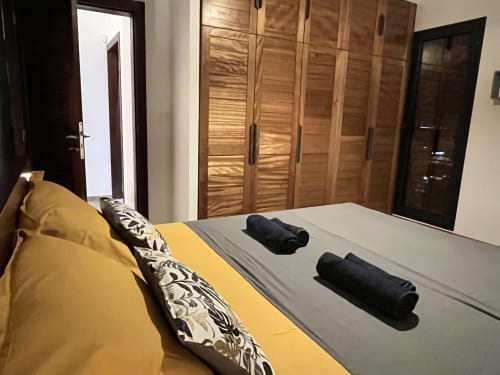Chambre spacieuse du gîte Les Hébergements Passion avec tête de lit jaune, coussins à motifs, serviettes roulées sur le lit, bois
