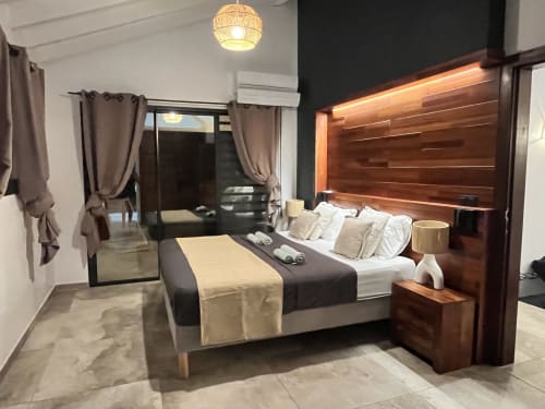 Chambre moderne aux Hébergements Passion en Martinique avec tête de lit en bois, literie de qualité et décoration contemporaine