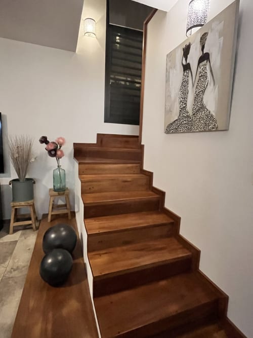 Escalier en bois aux Hébergements Passion en Martinique, murs blancs, décoration artistique et éclairage contemporain