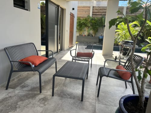 Terrasse contemporaine avec transats noirs à rayures, coussins rouges et plantes en pot aux Hébergements Passion
