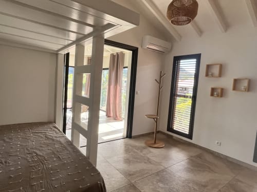 Chambre spacieuse des Hébergements Passion en Martinique avec mobilier moderne, carrelage et portes vitrées