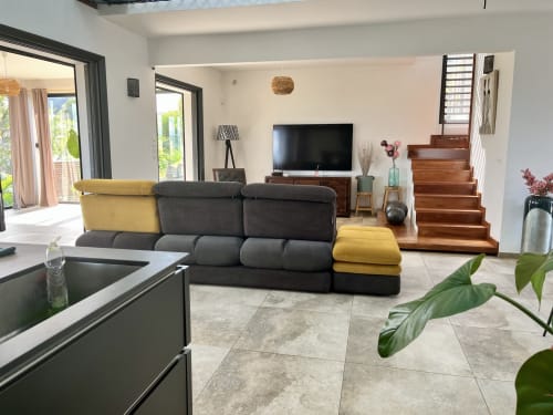 Séjour contemporain avec canapé modulable noir et jaune, téléviseur écran plat, mobilier en bois et accès à la terrasse