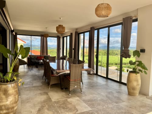 Intérieur de cottage moderne aux Hébergements Passion avec vue panoramique sur mer, salle à manger, salon et ambiance tropicale