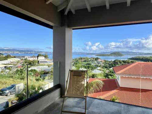 Terrasse couverte avec vue sur la baie de Martinique aux Hébergements Passion, Les Trois-Ilets, palmiers et