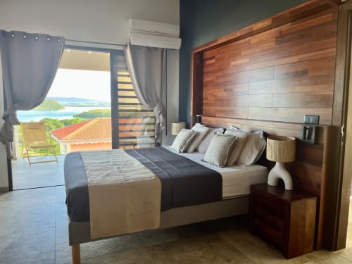 Chambre aux Hébergements Passion avec lit en bois, vue mer sur la Martinique depuis le balcon, climatisation