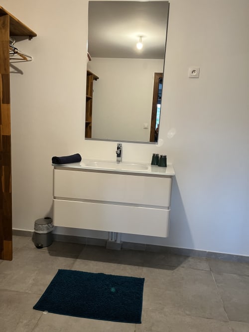Vanité de salle de bain moderne avec tiroirs blancs, miroir et lavabo au gîte Les Hébergements Passion, Martinique