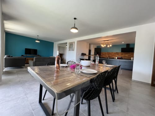 Cuisine et salle à manger ouvertes et modernes aux Hébergements Passion avec mur accent bleu-vert, table à manger en bois