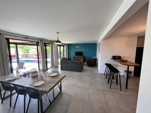 Séjour ouvert avec table à manger, coin bar et mur d'accent bleu-vert aux Hébergements Passion