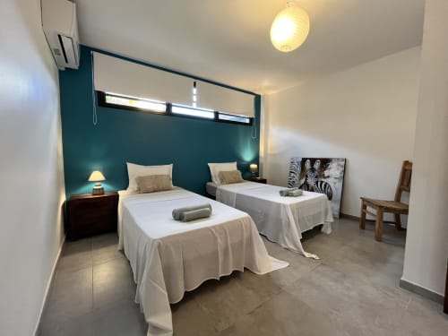Chambre twin avec mur d'accent bleu-vert aux Hébergements Passion en Martinique, draps blancs et design moderne