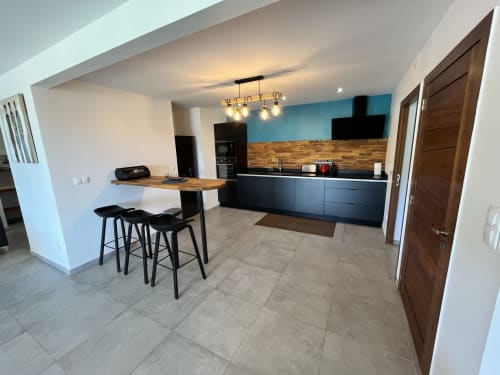 Cuisine moderne et coin repas de la maison d'hôtes Les Hébergements Passion en Martinique avec mobilier noir et bar en bois