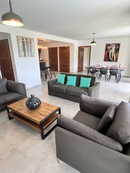 Espace de vie ouvert et moderne avec sièges gris, table en bois et coin repas au gîte Les Hébergements Passion