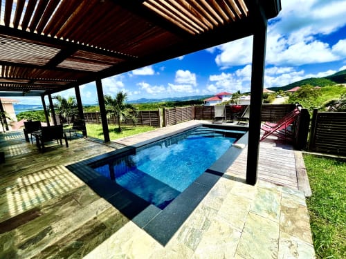 Piscine privée avec chaises longues sous une pergola en bois aux Hébergements Passion en Martinique, vue sur mer