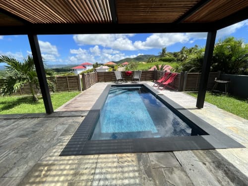 Piscine privée avec chaises longues et pergola en bois dominant les jardins tropicaux et les montagnes de la Martinique