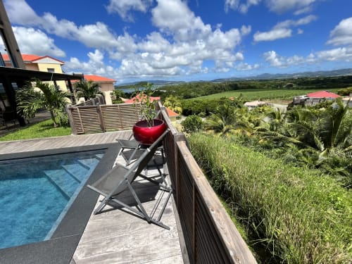 Terrasse privée avec chaise longue et coussin rouge surplombant la vallée de la Martinique au gîte Les Hébergements Passion
