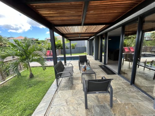Patio couvert avec chaises longues et pergola en bois surplombant le jardin tropical de la maison d'hôtes Les Hébergements Passion