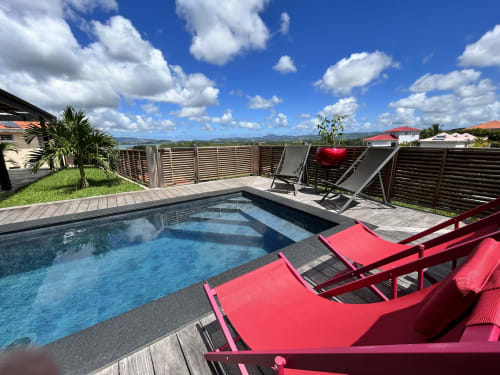 Piscine privée avec transats rouges et vue sur la mer au gîte Les Hébergements Passion en Martinique