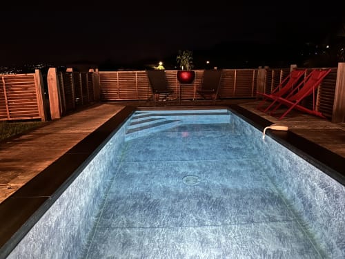 Piscine privée vide la nuit avec terrasse en bois et chaises longues rouges, Les Trois-Ilets, Martinique