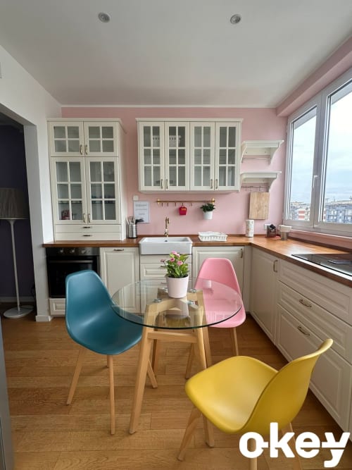 Cucina moderna con pareti rosa, mobili color crema e sedie colorate intorno al tavolo rotondo nell'appartamento di Bari