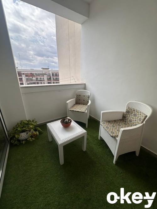 Luminosa zona soggiorno in balcone con sedie in rattan bianco e erba sintetica verde presso l'appartamento B&B Bari Centro in Italia