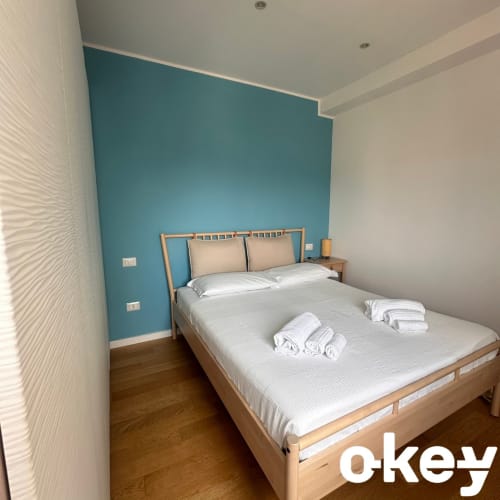 Camera moderna presso Casetta Lilla Stay con parete in azzurro tiffany, letto in legno, biancheria bianca e pavimento in parquet a Bari