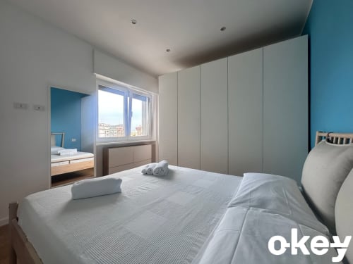 Camera moderna a Casetta Lilla Stay a Bari con letto matrimoniale, guardaroba con specchio, parete azzurra e vista sulla città