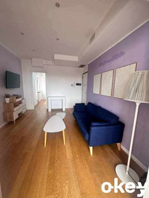 Soggiorno moderno a Bari con parete in viola, divano blu navy, pavimento in legno e arredi contemporanei