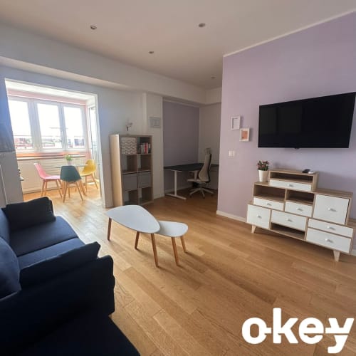 Moderno monolocale con pareti rosa, TV a schermo piatto, divano nero e arredi in legno a Bari, Italia