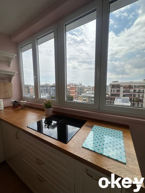 Moderno spazio di lavoro con scrivania in legno, laptop e vista panoramica su Bari da ampi finestroni presso Casetta Lilla Stay