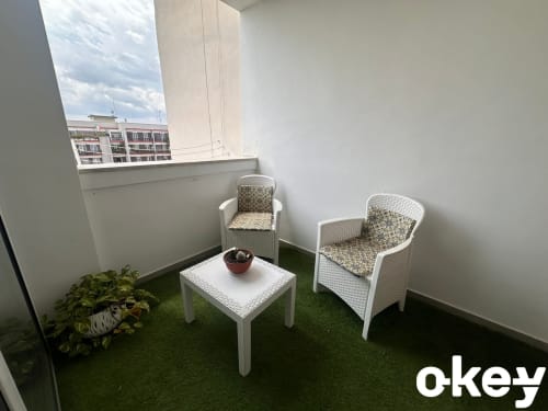 Elegante zona lounge su balcone con sedie in vimini bianco, cuscini decorativi e erba sintetica all'appartamento Bari Centro