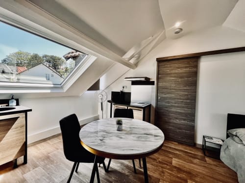 Studio loft contemporain avec table à manger en marbre, puits de lumière et mobilier en bois à La Villa L'Oiseau Bleu