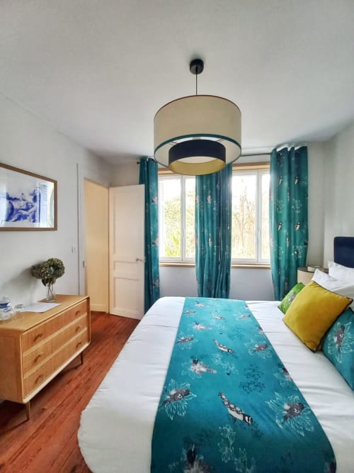 Chambre Suite Deluxe lit king à la Villa Eliane, Étretat avec rideaux motif bleu-vert, commode en bois et vue jardin