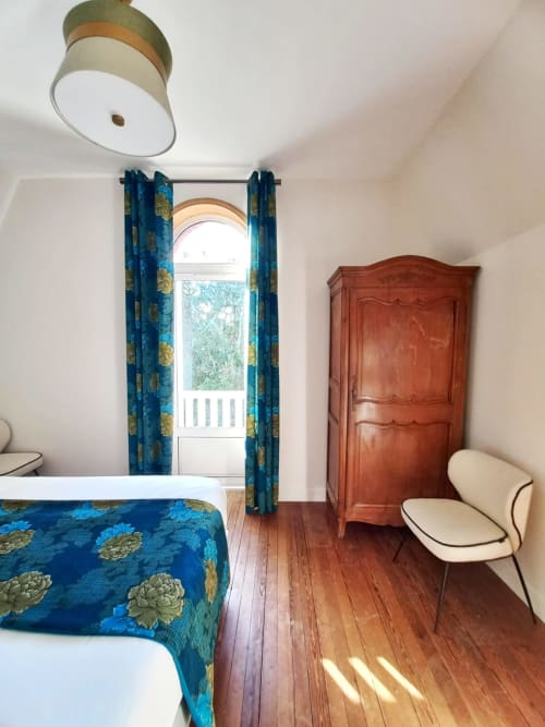 Bright bedroom at Villa Eliane B&B in Étretat with blue patterned bedding, wooden wardrobe, and garden views