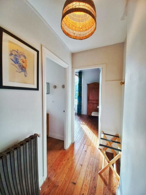 Hallway at Villa Eliane Étretat with hardwood floors, wicker ceiling lamp, and open bedroom doors