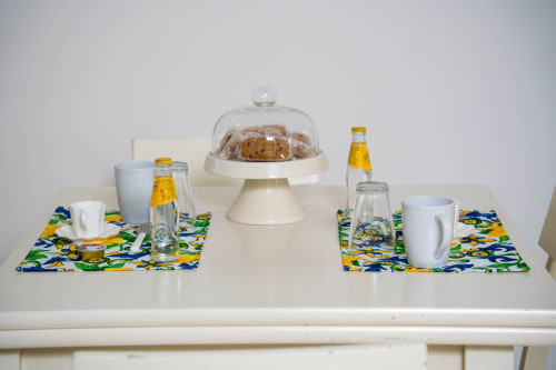 Elegant table setting with decorative placemats, beverages, cookies under a dome, and white cups at Sorrento Sea View