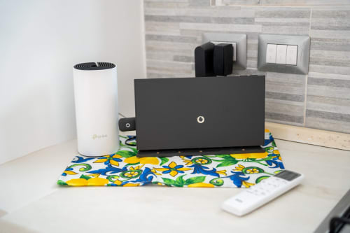 Desk setup at Sorrento Sea View with WiFi router, cable organizer, and remote control in The Cave On The Sea apartment