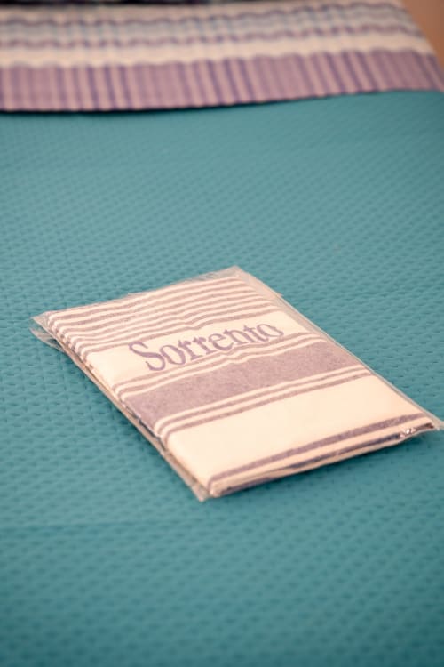 Sorrento branded towel with purple stripes on turquoise mat at Sorrento Sea View hotel in Meta, Italy
