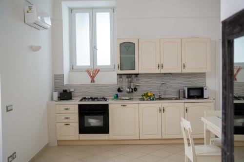 Modern kitchen in The Cave On The Sea apartment at Sorrento Sea View with cream cabinets, gas stove, and dining area