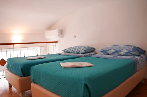 Bright bedroom at Sorrento Sea View with twin beds, teal bedding, and air conditioning in Meta, Italy