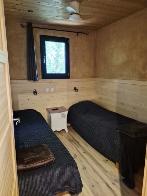 Gemütliches Schlafzimmer im Domaine en Terre Happy mit zwei Einzelbetten, Holzwänden und Gartenblick