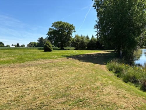 Camping spacieux aux Rives du bel air avec pelouse, arbres et accès au bord de l'eau en France