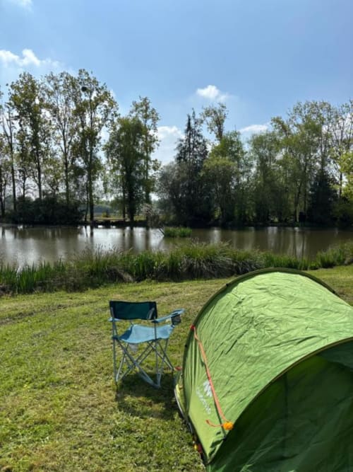 Tente verte et chaise de camping au bord du lac aux Rives du bel air, camping en countryside français