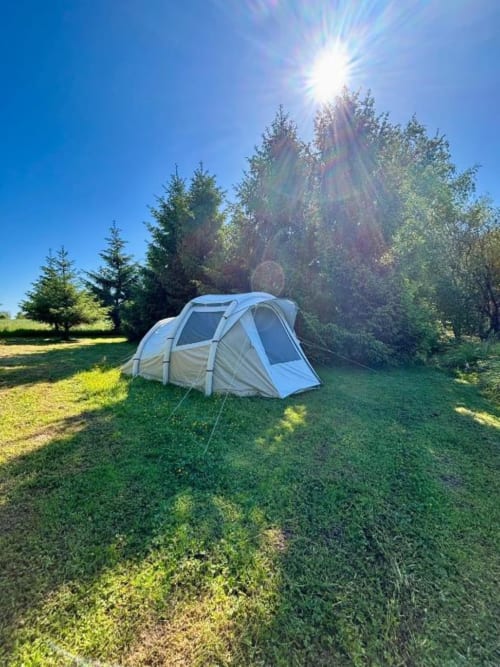 Spacieux hébergement en tente aux Rives du bel air entouré d'herbe verte et d'arbres sous un beau soleil