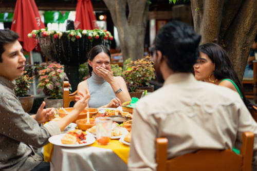 Amigos cenando juntos en Villa Merida Boutique Hotel en Mérida, México, disfrutando de la comida y la conversación en un ambiente vibrante