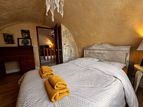 Chambre rustique du gîte Le Rupicapra à Roubion avec lit blanchi à la chaux, serviettes jaunes et murs ocre texturés